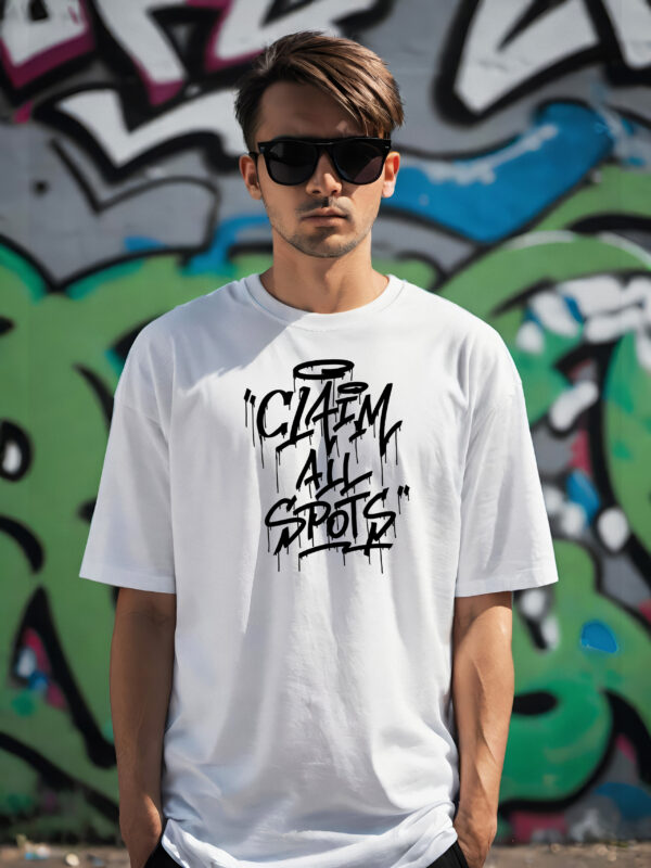 man wearing the all new Claim All Spots T--shirt in front of a graffiti wall
